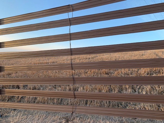 Brown plastic strips forming a snow fence in a field, illustrating BioPlastic Solutions' custom profile extrusion capabilities.