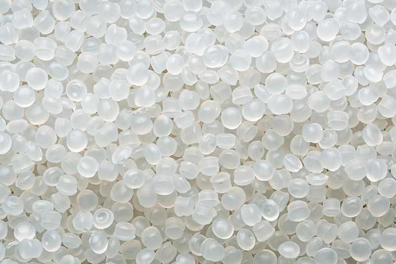 Close-up of translucent flexible PVC pellets, used in custom plastic extrusion manufacturing.