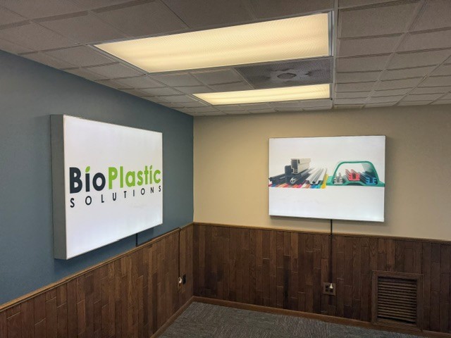 BioPlastic Solutions office interior featuring illuminated signs displaying the company logo and various plastic extrusion products.
