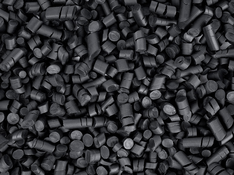 Close-up of black rigid PVC pellets used in plastic extrusion manufacturing.