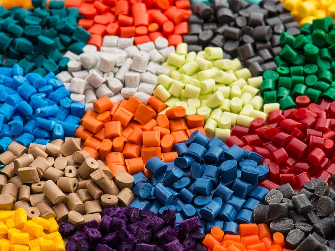 Colorful assortment of bio-based plastic pellets arranged in piles, showcasing the variety of options available for sustainable resin solutions.