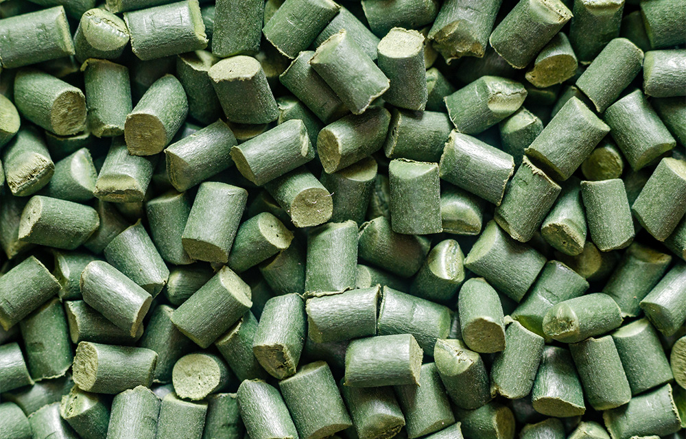 Green bioplastic pellets used in sustainable extrusion manufacturing.