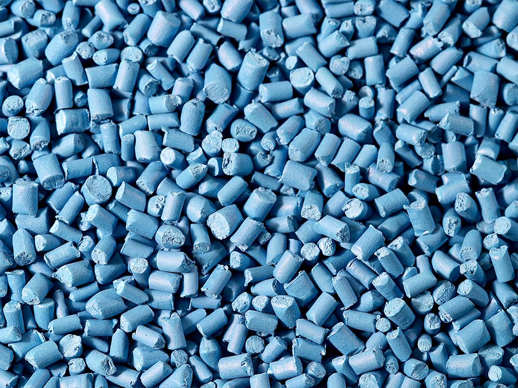 Close-up of blue plastic resin pellets, representing BioPlastic Solutions' innovative bio-resin development for sustainable manufacturing.
